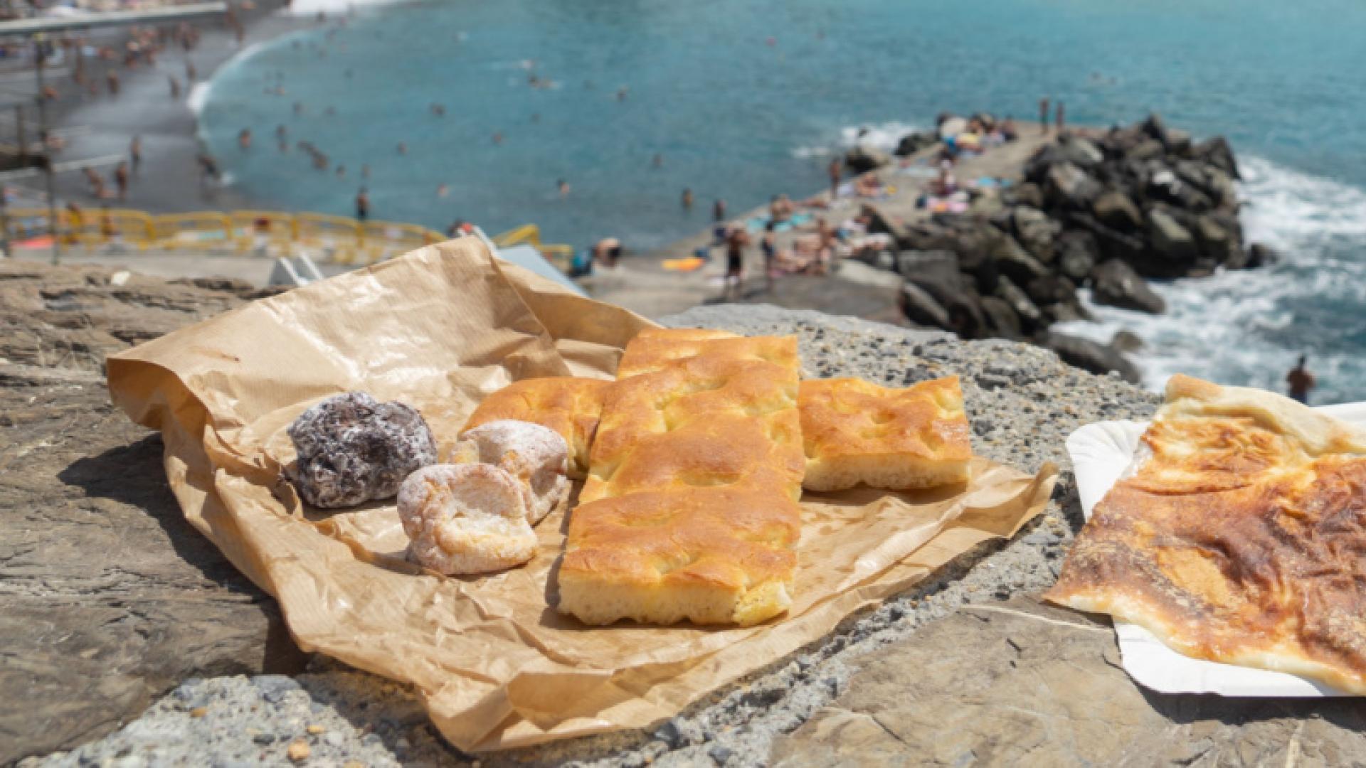 Focaccia e dolci su una scogliera con vista sul mare.