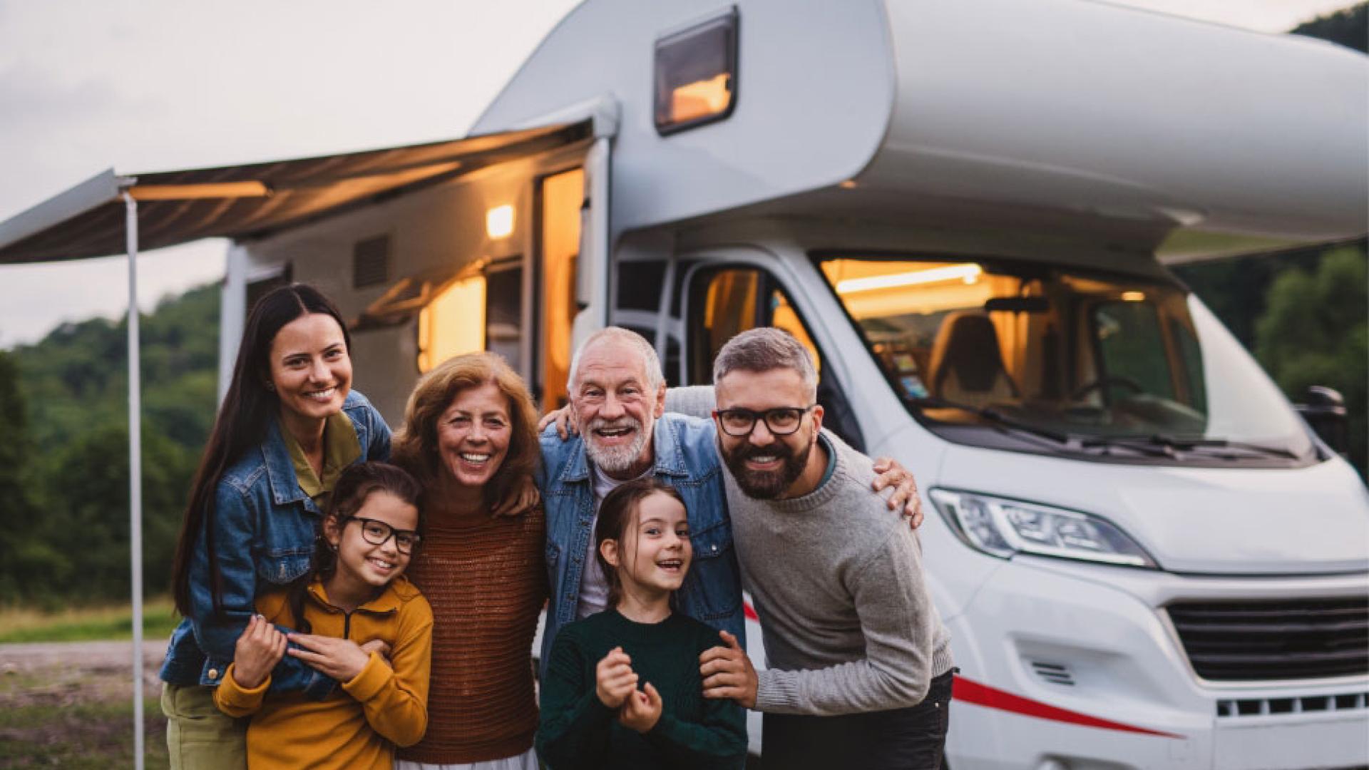 Famiglia felice in campeggio, sorrisi e abbracci davanti a un camper.
