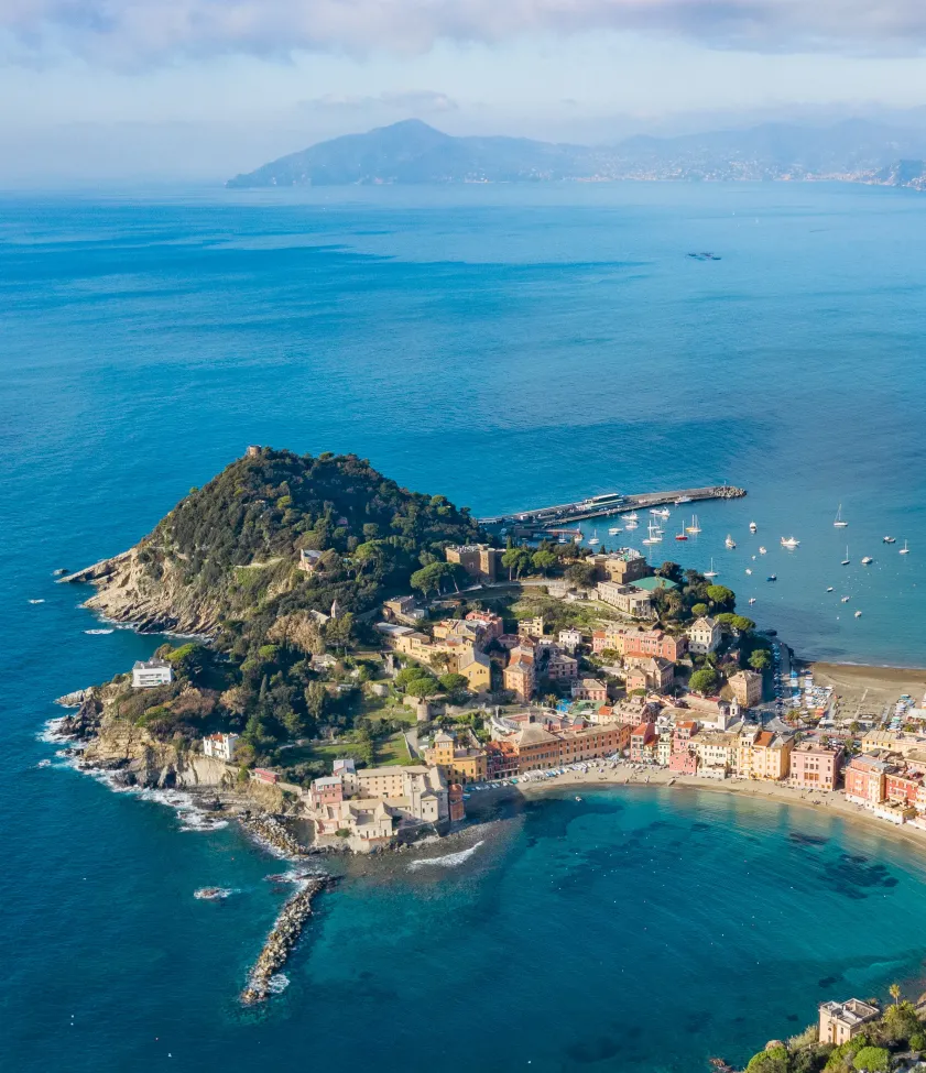 Vista aerea di una città costiera con colline e mare cristallino.